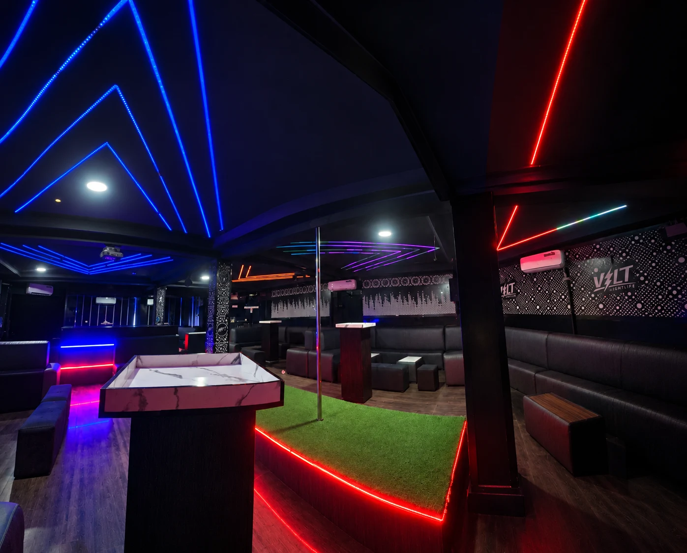Club platform and seating beneath blue and red neon ceiling lights