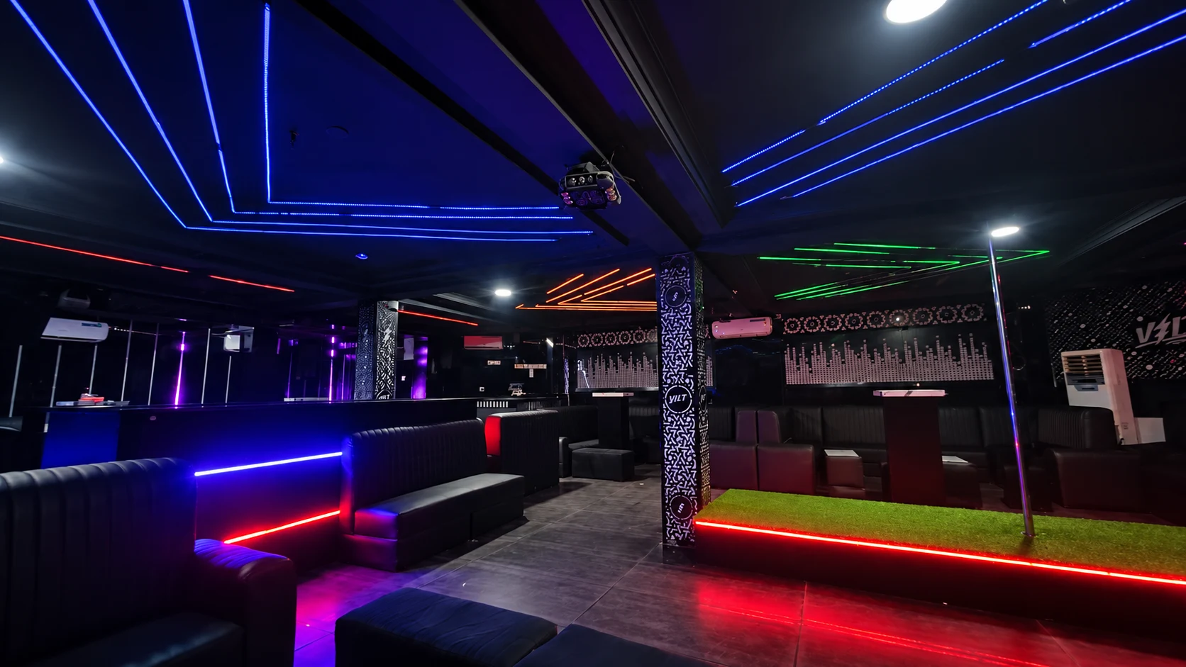 Wide view of the club floor with ceiling LEDs, raised platform and lounge seating