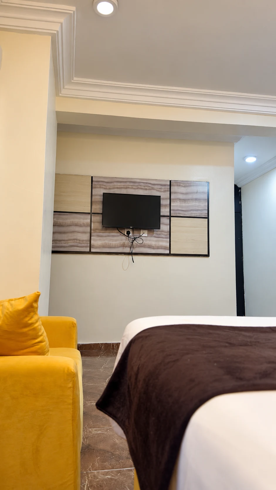 Executive Room bed, yellow lounge chair and television wall