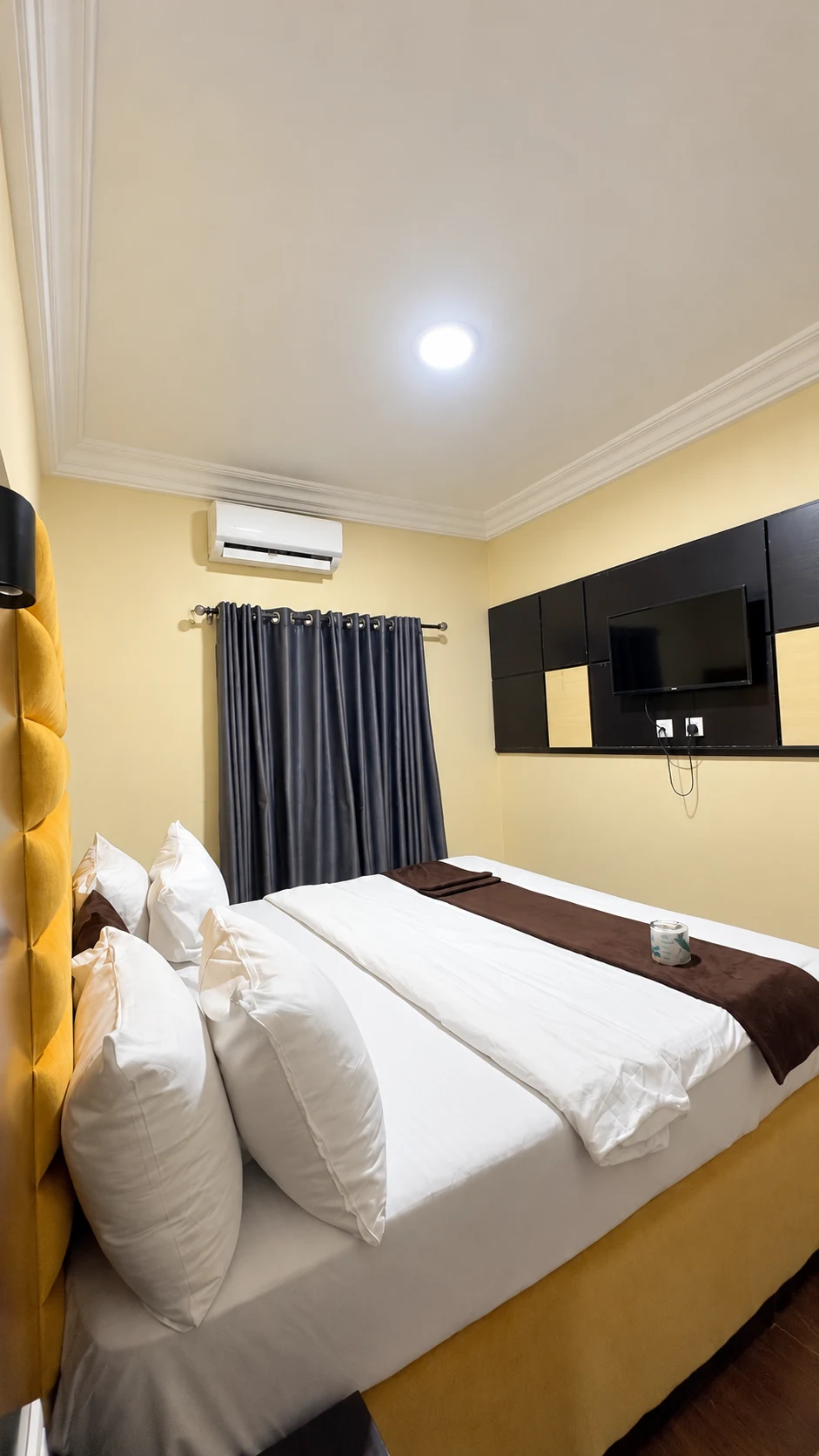 Standard Room bed from the side with television and air conditioning